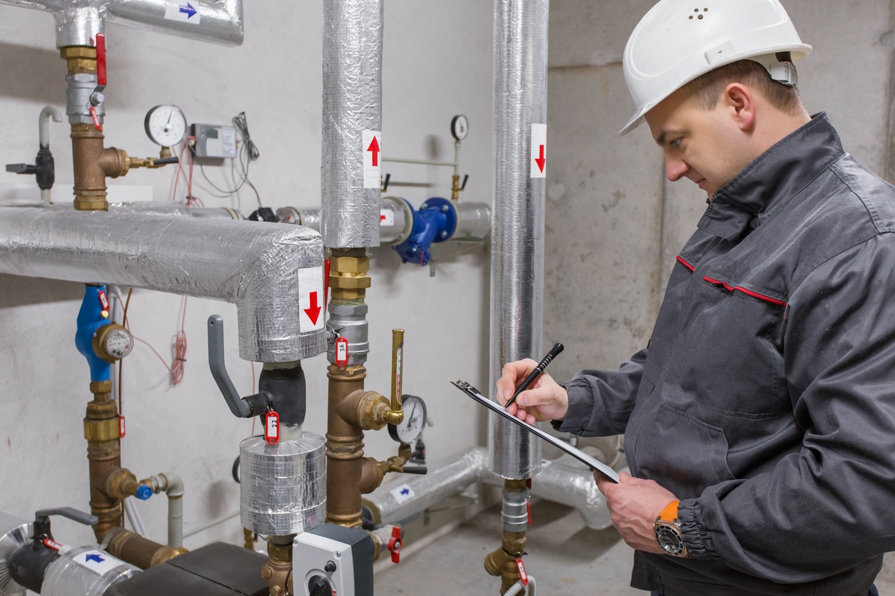 Engineer inspecting heating system in boiler room.